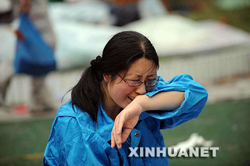 5月14日，张关蓉在丈夫谭千秋的遗体旁痛哭。 受汶川地震影响，四川省德阳市东汽中学教学楼坍塌。在地震发生的一瞬间，该校教导主任谭千秋双臂张开趴在课桌上，身下死死地护着4个学生，4个学生都获救了，谭老师却不幸遇难。 新华社记者王建华摄 