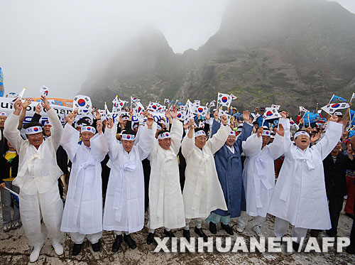  7月14日，大批韩国人在独岛（日本称“竹岛”）手举国旗抗议。韩国外交通商部发言人文太暎当日发表声明，强烈抗议日本在当天公布的中学教科书指导手册中将独岛（日本称“竹岛”）表述为日本领土，并要求日本立即对有关内容进行修正。韩国外交通商部将采取召回韩国驻日本大使和召见日本驻韩国大使这两项外交措施，就此问题向日本政府表示强烈抗议。 新华社/法新 