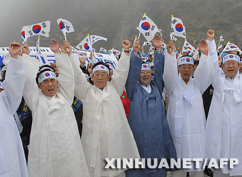 7月14日，大批韩国人在独岛（日本称“竹岛”）手举国旗抗议。韩国外交通商部发言人文太暎当日发表声明，强烈抗议日本在当天公布的中学教科书指导手册中将独岛（日本称“竹岛”）表述为日本领土，并要求日本立即对有关内容进行修正。韩国外交通商部将采取召回韩国驻日本大使和召见日本驻韩国大使这两项外交措施，就此问题向日本政府表示强烈抗议。 新华社/法新 