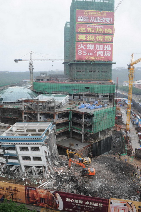 5月21日，工程机械在拆除绵阳紫荆民族中学校舍，旁边则是建设中的万达广场。